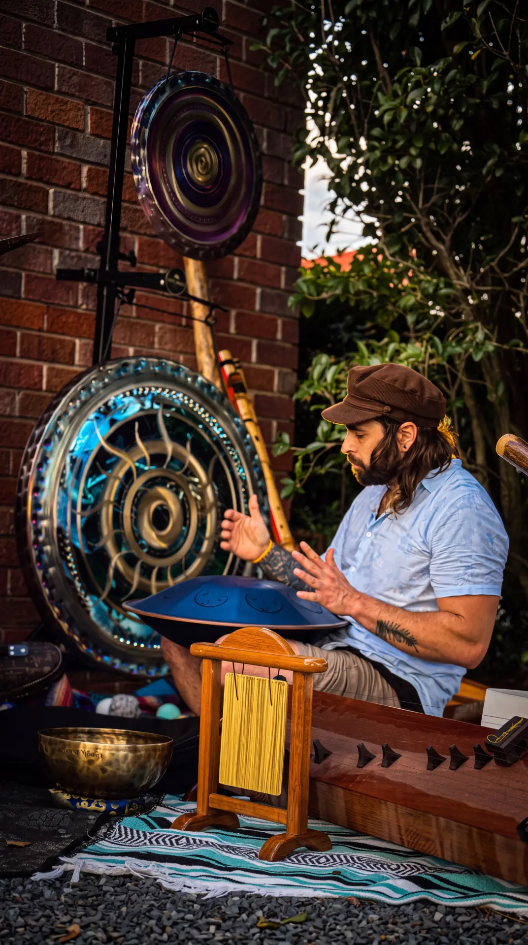 Benny playing a handpan surrounded by gongs, chimes, and a guzheng
